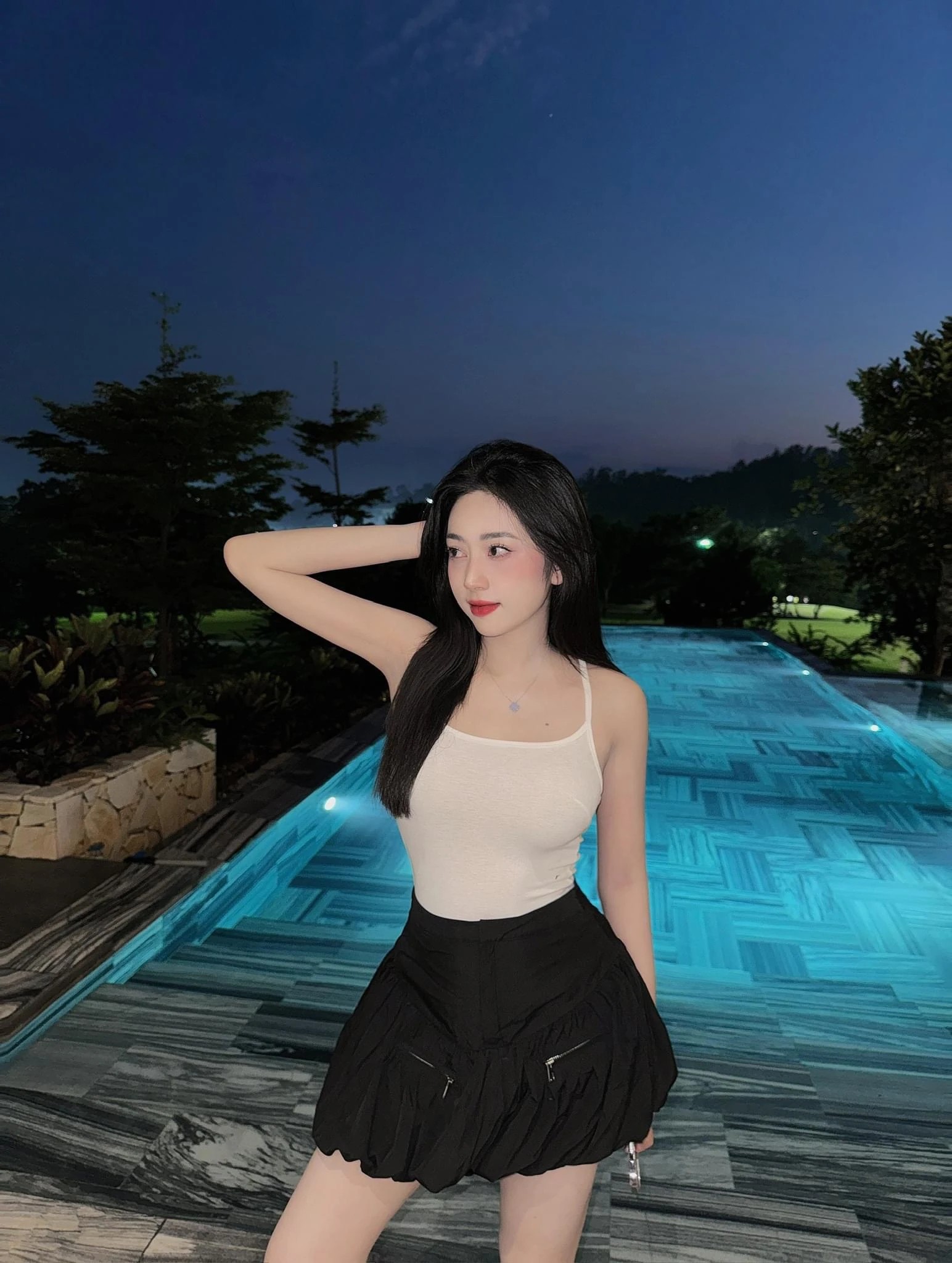 Khách nữ áo trắng váy đen bên bể bơi đêm blue hour không gian giải trí Moon Villa
