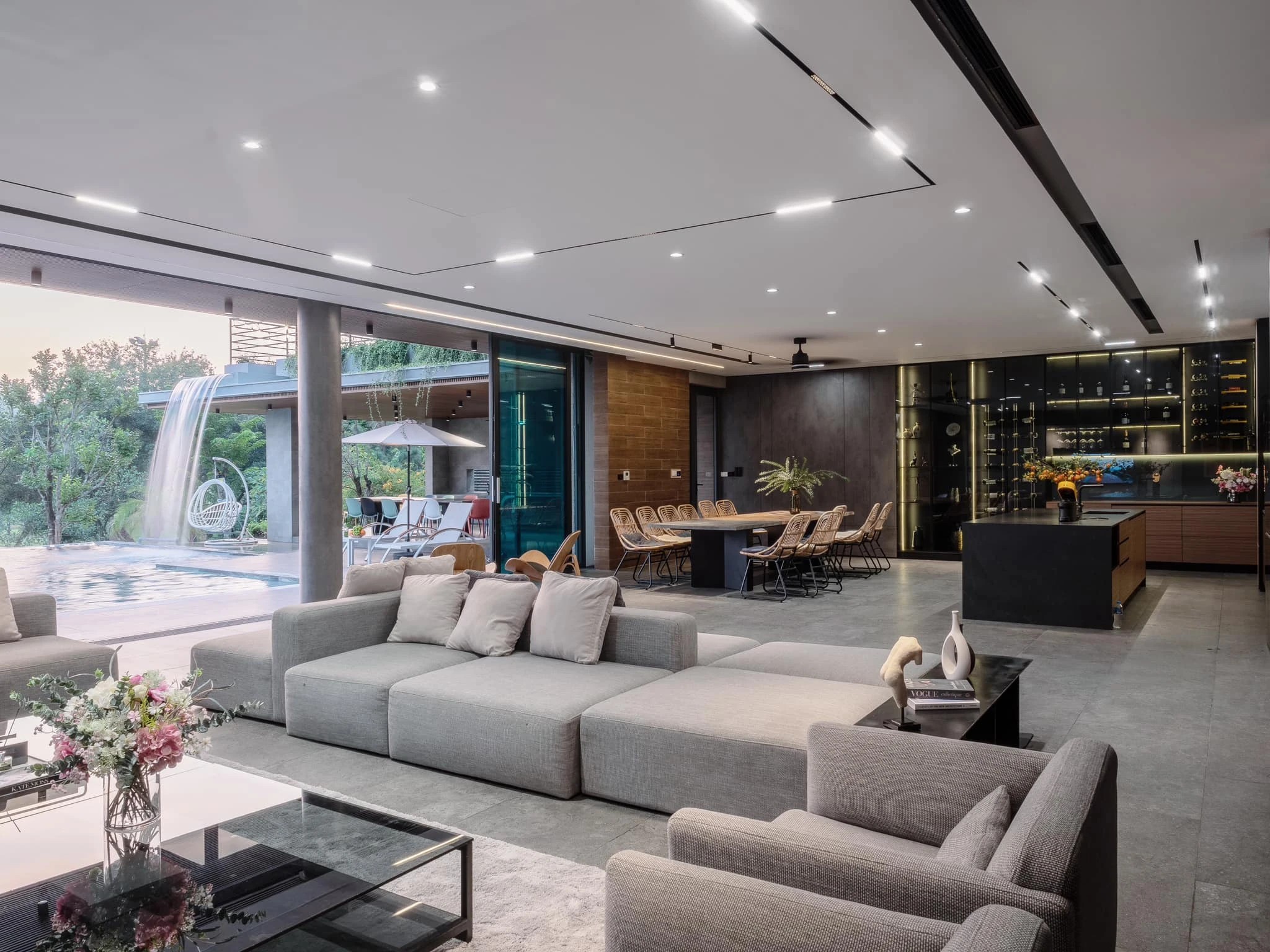 Phòng khách open-plan + bếp đảo + dining + thác nước qua cửa wide-open Moon Villa C27